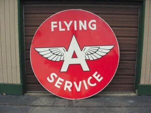 A vintage signs with the words "Flying Service" in white bold letters, against a clear red background.